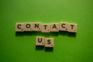 The words 'Contact Us' spelled out using scrabble letters, on bright green background